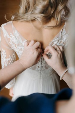 Düğünde ailenle fotoğraf çektirmek. Mutlu ebeveynler yakında evlenecek olan kızları için yardım eder ve sevinirler. Düğünde dokunaklı anlar. Anne kızının gelinliğini bağlar.