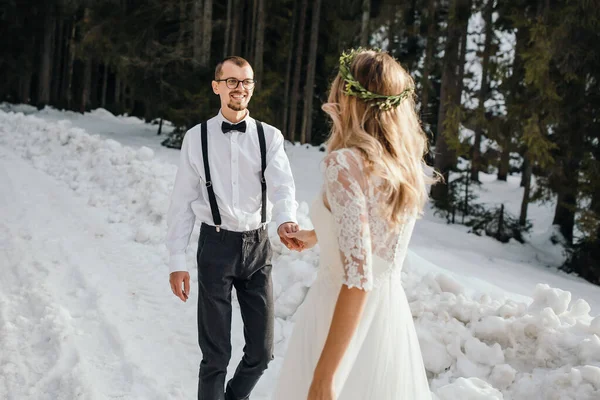 Bruden Och Brudgummen Springer Längs Snöig Väg Mot Bakgrunden Tallskog — Stockfoto