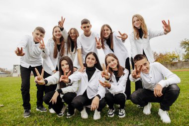 Bir grup mutlu genç aynı kıyafeti giyip üniversitenin yakınındaki bir stadyumda poz veriyorlar. Arkadaşlık kavramı, mutluluk anları. Okul arkadaşlığı