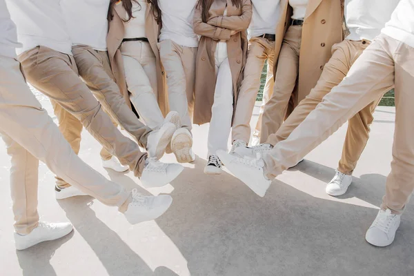 Friendship, movement, action, freedom and people concept - group of happy teenagers or school friends posing and having fun outdoors. Cropped photo of people who raised their legs.