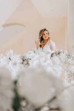 Gelinin düğünden önceki sabahı. Duvağı ve güzel bir saç stili olan güzel, genç bir kadın. Beyaz bir bornozla, harika bir iç mekanı olan bir odada. Doğal güzellik ve profesyonel makyaj..