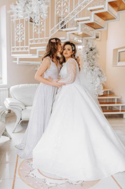 Bir arkadaş gelinin elbisesini bağlamasına yardım ediyor. Bir kadın arkadaşının gelinliğinin arkasındaki düğmeleri bağlamasına yardım eder. Gelinin sabahı, bir aile kurmak, önemli bir olay..