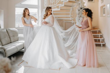 Bir arkadaş gelinin elbisesini bağlamasına yardım ediyor. Bir kadın arkadaşının gelinliğinin arkasındaki düğmeleri bağlamasına yardım eder. Gelinin sabahı, bir aile kurmak, önemli bir olay..