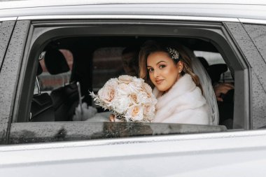 Pahalı bir arabanın vitrininde inanılmaz güzel bir gelinin portresi. Elinde bir buket çiçekle gelin kameranın lensine bakar..