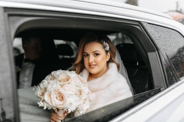 Pahalı bir arabanın vitrininde inanılmaz güzel bir gelinin portresi. Elinde bir buket çiçekle gelin kameranın lensine bakar..