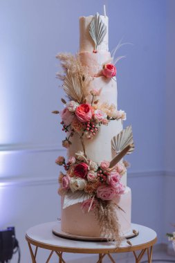 Ziyafet salonunda taze çiçeklerle süslenmiş çok katlı bir düğün pastası. Düğün kutlaması için hazırlık. Düğün pastasını kesiyorum..