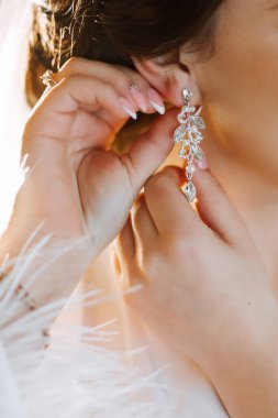 Küpe takan yumuşak saten iç çamaşırlı güzel bir kızın yakın çekimi. Gelinin düğün sabahı. Reklam dekorasyonları. Bir kadın randevuya çıkar..