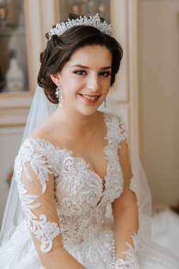 Şık bir gelinlik içinde, şık bir düğün saç stili ve profesyonel makyajlı güzel bir gelin. Sabahtan beri odadaki genç ve güzel gelinin yakın plan portresi. Yüksek kalite fotoğraf.