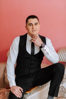 Damadın şık bir portresi. Bir adam sabahki düğün törenine hazırlanır. Damat sabahı. Damadın sabahı için hazırlık. Şık takım elbiseli genç ve yakışıklı damat..