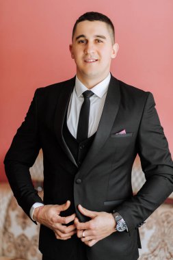 Damadın şık bir portresi. Bir adam sabahki düğün törenine hazırlanır. Damat sabahı. Damadın sabahı için hazırlık. Şık takım elbiseli genç ve yakışıklı damat..