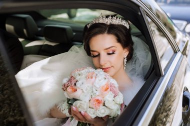 Pahalı bir arabanın vitrininde inanılmaz güzel bir gelinin portresi. Elinde bir buket çiçekle gelin usulca çiçeklere bakar..