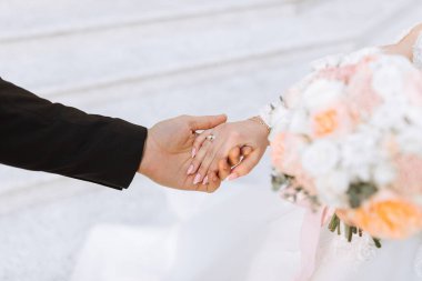 Damat, nikah töreninde parmağına bir alyans taktıktan sonra nazikçe gelinin elini tutar. Soğuk mevsimde güzel bir düğün.