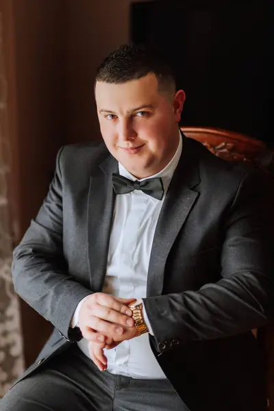 Stylish portrait of the groom. A man prepares for a wedding ceremony in the morning. Groom's morning. Preparation for the groom's morning. Young and handsome groom in a stylish suit.
