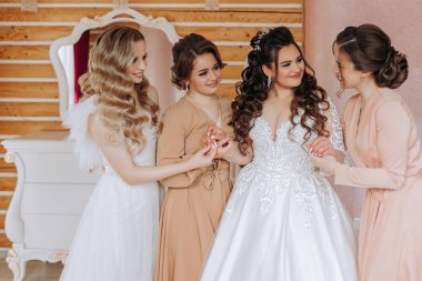 Arkadaşlar sabah gelinle sevinirler. Fotoğraf çekerler, gülümserler, gelinin elbisesini bağlamasına yardım ederler..