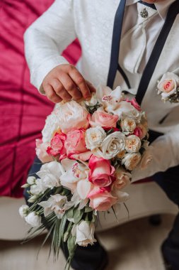 Bir buket çiçekle damadın şık portresi. Bir adam sabahki düğün törenine hazırlanıyor. Damat sabahı. Damadın sabahı için hazırlık. Genç ve yakışıklı damat.