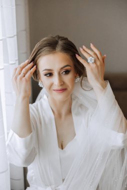 Saçında taç olan güzel bir esmer gelin güzel bir bornozla düğün için hazırlanıyor. Yakın plan düğün fotoğrafı, fotoğraf..