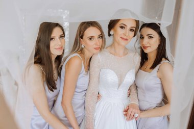 Arkadaşlar sabah gelinle sevinirler. Fotoğraf çekerler, gülümserler, gelinin elbisesini bağlamasına yardım ederler..