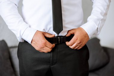 Damadın sabahında, damat düğün töreni için hazırlanır takım elbise ve ayakkabı giyer. Bir adam siyah kuşak takıyor.