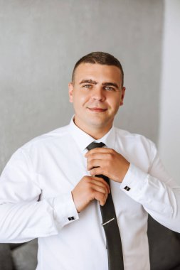 Şık bir damat düğün törenine hazırlanmak için kravatını bağlıyor. Damat sabahı. Bir iş adamı kravat takar. Damat düğün töreninden önce hazırlanıyor..