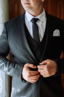 Adam ceketinin düğmelerini bağlıyor. Damat düğün töreni için hazırlanıyor. Ellerin detaylı yakın plan fotoğrafı.