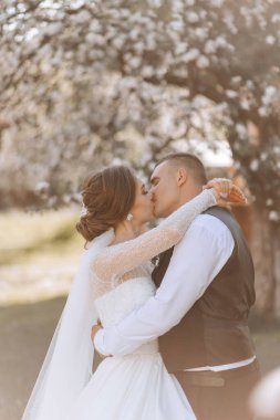 Düğün için. Aşk ve çift düğün için bahçede. Törenin ve bağlılığın kutlanması. Tarihi kaydet. Güven. Gelin ve damat kucaklaşır. Gülümse ve sev. Damat gelini kucaklar ve öper..