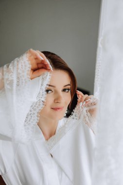 Saçında taç olan güzel bir esmer gelin güzel bir bornozla düğün için hazırlanıyor. Yakın plan düğün fotoğrafı, fotoğraf..