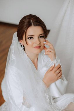 Saçında taç olan güzel bir esmer gelin güzel bir bornozla düğün için hazırlanıyor. Yakın plan düğün fotoğrafı, fotoğraf..
