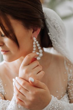 Küpe takan yumuşak saten iç çamaşırlı güzel bir kızın yakın çekimi. Gelinin düğün sabahı. Reklam dekorasyonları. Bir kadın randevuya çıkar..