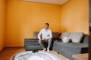 Damat sabahki düğün töreni için odasında hazırlanıyor. Damat sabahı. Damadın sabahı için hazırlık. Damat bir ceket giyer. Olgun bir adamın kendine güveni..