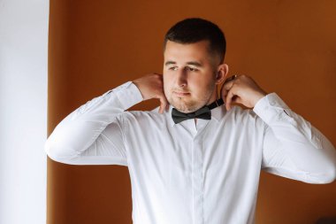 Şık bir damat düğün törenine hazırlanmak için kravatını bağlıyor. Damat sabahı. Bir iş adamı kravat takar. Damat düğün töreninden önce hazırlanıyor..