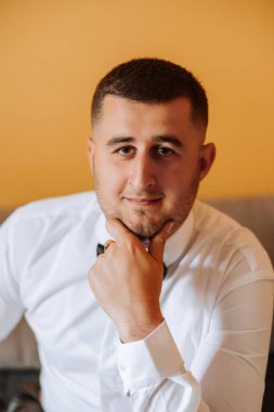 Sabahki düğün törenine hazırlanan damadın şık bir portresi. Damat sabahı. Damadın sabahı için hazırlık. Damat bir ceket giyer. Olgun bir adamın kendine güveni..