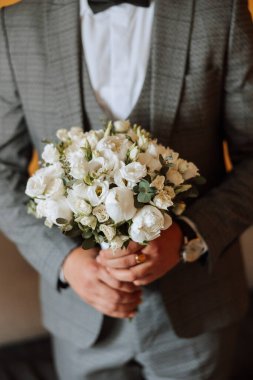 Bir buket çiçekle damadın şık portresi. Bir adam sabahki düğün törenine hazırlanıyor. Damat sabahı. Damadın sabahı için hazırlık. Genç ve yakışıklı damat.