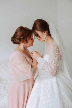 Güzel ve mutlu bir anne ve kızı, gelin, yan yana duruyorlar. Ebeveynler için en iyi gün. Düğünde hassas anlar.