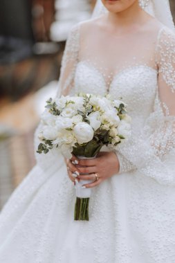 Gelin bir düğün buketi tutuyor. Kesilmiş fotoğraf. Düğündeki detaylar. Beyaz dantel elbise