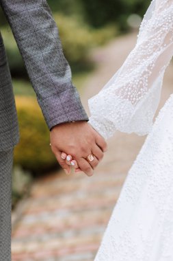 Damat gelinin elini tutuyor. Kesilmiş fotoğraf. Gri takım elbiseli damat. Ayrıntılar