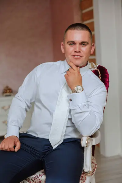 A stylish portrait of the groom preparing for the wedding ceremony in the morning. Groom\'s morning. Preparation for the groom\'s morning. The groom puts on a jacket. The confident look of a mature man.