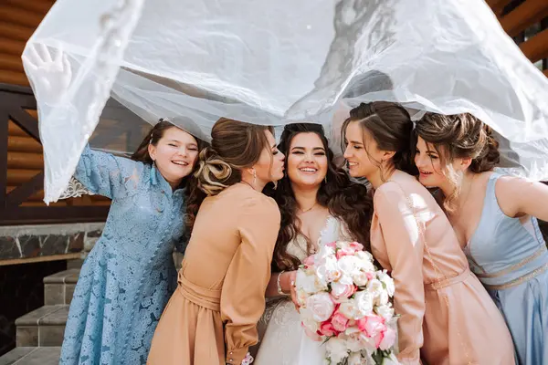 Group portrait of the bride and bridesmaids. A bride in a wedding dress and bridesmaids in beautiful dresses hold the bride\'s bouquet on the wedding day.