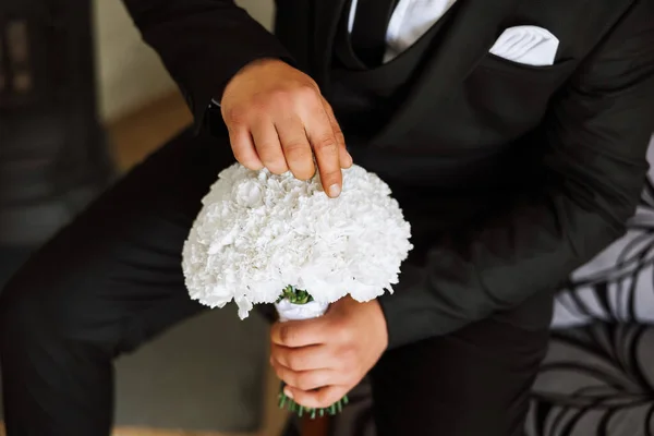 Stylish portrait of the groom with a bouquet of flowers. A man is preparing for a wedding ceremony in the morning. Groom\'s morning. Preparation for the groom\'s morning. Young and handsome groom.