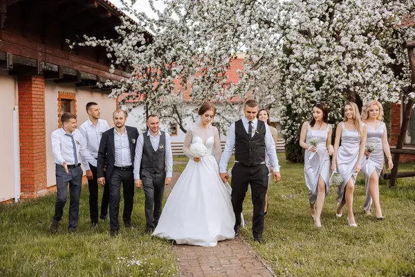 full-length portrait of the newlyweds and their friends at the wedding. The bride and groom with bridesmaids and friends of the groom are having fun and rejoicing at the wedding.