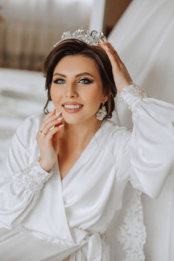Saçında taç olan güzel bir esmer gelin güzel bir bornozla düğün için hazırlanıyor. Yakın plan düğün fotoğrafı, fotoğraf..