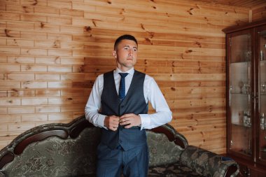 Damat, damadın sabah toplantılarında yeleğine bir düğme takar. Damat düğün hazırlığı.