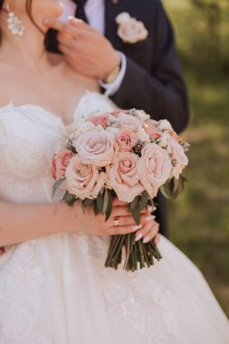 Gelin bir düğün buketi tutuyor. Kesilmiş fotoğraf. Düğündeki detaylar. Beyaz dantel elbise