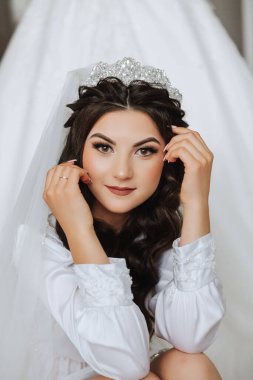 Saçında taç olan güzel bir esmer gelin güzel bir bornozla düğün için hazırlanıyor. Yakın plan düğün fotoğrafı, fotoğraf..