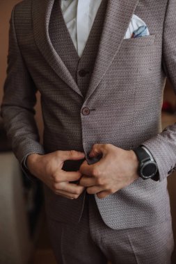 Adam ceketinin düğmelerini bağlıyor. Damat düğün töreni için hazırlanıyor. Ellerin detaylı yakın plan fotoğrafı.