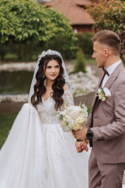 Düğün töreninden sonra bahçede yürüyen genç bir gelin ve damadın portresi. Gelin ve damat güzel bir bahar çiçekleri parkında yürüyorlar. Mutlu evlilik çifti, kopyalama alanı