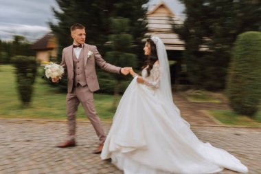 Düğün töreninden sonra bahçede yürüyen genç bir gelin ve damadın portresi. Gelin ve damat yürüyor. Fotoğraf bulanık bir şekilde çekildi. Mutlu evlilik çifti.
