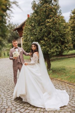 Düğün töreninden sonra bahçede yürüyen genç bir gelin ve damadın portresi. Gelin ve damat güzel bir bahar parkında yürüyorlar. Mutlu evlilik çifti, kopyalama alanı