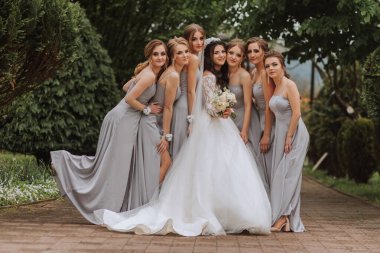 Gelin ve nedimelerin toplu portresi. Gelinlik giymiş bir gelin ve gümüş elbiseli nedimeler düğün günlerinde şık buketler tutarlar..