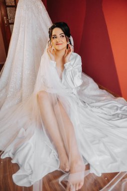 Saçında taç olan güzel bir esmer gelin güzel bir bornozla düğün için hazırlanıyor. Yakın plan düğün fotoğrafı, fotoğraf..