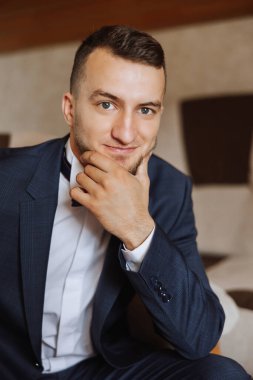 Sabahki düğün törenine hazırlanan damadın şık bir portresi. Damat sabahı. Damadın sabahı için hazırlık. Damat bir ceket giyer. Olgun bir adamın kendine güveni..